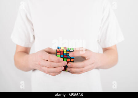 Teenager Geschwindigkeit Lösung 5 x 5 Würfel Puzzle im weißen T-Shirt mit weissem Hintergrund Stockfoto