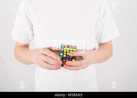 Teenager Geschwindigkeit Lösung 5 x 5 Würfel Puzzle im weißen T-Shirt mit weissem Hintergrund Stockfoto