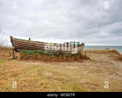 Abgebrochene Fischerboot auf Bank von Meer. Morgen stille Bucht innerhalb windstill. Dramatische und malerische Szene. Dark Sky in Wasser spiegel Stockfoto