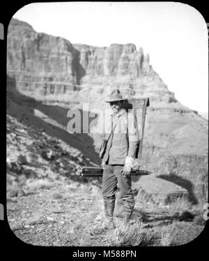 Grand Canyon Matthes Übersicht von. Schwarz und Weiß GLAS LATERNE FOLIE MANN MIT UMFRAGE ANLAGEN (d. h. Stativ und Flat Pack) im Canyon. Kleidung MÖGLICHKEIT MILITÄRISCHE GOLD LINIEN AN DER SEITE DES BILD AUF EINER SEITE DER FOLIE, USGS ETIKETT OHNE INFORMATIONEN CIRCA 1902. Mit EINER GRUPPE VON FOLIEN AUS DER MATTHES UMFRAGE EXPEDITION IM GRAND CANYON - ca. 1902 Stockfoto