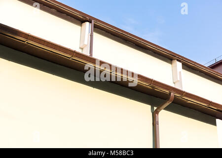 Putz an der Wand des Hauses mit Rinne und Fallrohr auf blauen Himmel Hintergrund Stockfoto