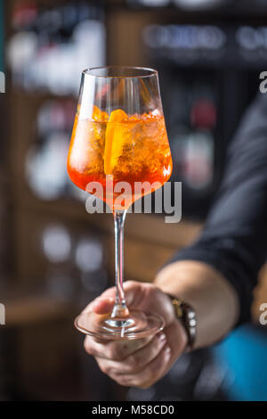 Aperol Spritz trinken. Barkeeper hand Glas mit Aperol Spritz trinken. Stockfoto