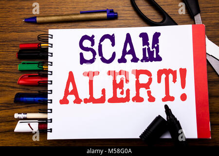 Handschrift Ansagetext angezeigt Scam Alert. Business Konzept für Betrug Warnung auf dem Notebook geschrieben, Holz- hintergrund Bürogeräte wie Stifte Stockfoto