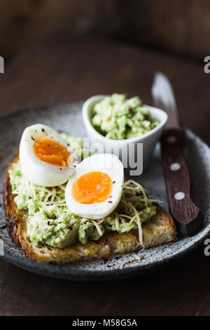 Guacamole, Ei und Käse auf Toast. Gesunde Lebensweise, gesunde Ernährung Konzept. Dunkle essen Foto, selektiver Fokus Stockfoto