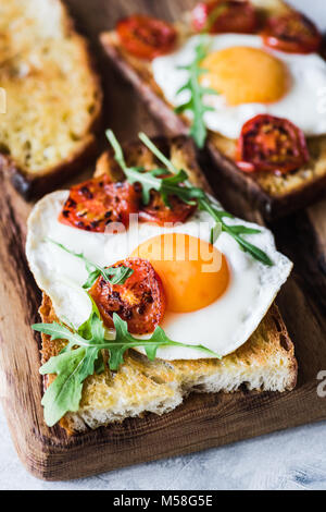 Frühstück Toast mit Ei, gerösteten Tomaten und Rucola Salat. Detailansicht Stockfoto