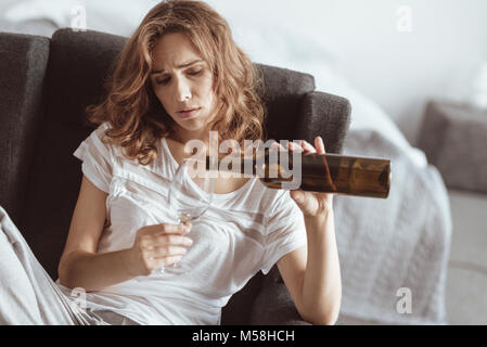 Betonte Frau Wein zu Hause gießen Stockfoto