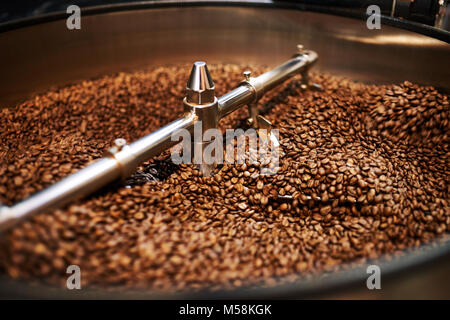 Edelstahl arme Mischen frisch gerösteten Kaffeebohnen in großen Edelstahl Kühlung drum, wo die Bohnen abgekühlt werden vor dem Verpacken oder sto Stockfoto