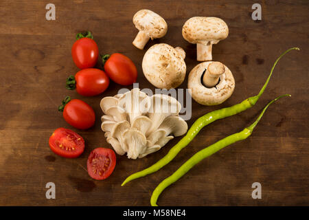 Gemüse: Blick von oben auf die Auster und Champignons mit roten Baby Tomaten isoliert auf braunem Holz- Hintergrund Stockfoto