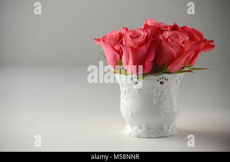 Blumenstrauß aus Rosen in einer weißen Vase auf einem grauen Hintergrund mit kopieren. Grußkarte Hintergrund. Stockfoto