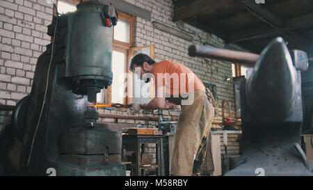 Man Schmied schmiedet das Metall an der mechanischen Hammer Stockfoto