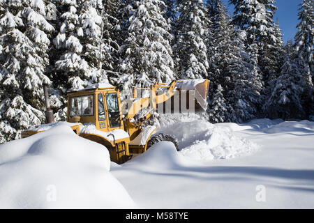 02/19/2018 Snow event. Ein Caterpillar 950 mit Gummibereifung artikuliert Lader Schneeräumen auf einem Berg Straße nördlich des Noxon, in Sanders County Montana. Stockfoto