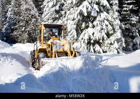 02/19/2018 Snow event. Ein Caterpillar 950 mit Gummibereifung artikuliert Lader Schneeräumen auf einem Berg Straße nördlich des Noxon, in Sanders County Montana. Stockfoto