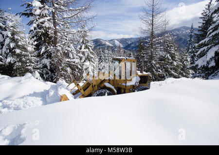 02/19/2018 Snow event. Ein Caterpillar 950 mit Gummibereifung artikuliert Lader Schneeräumen auf einem Berg Straße nördlich des Noxon, in Sanders County Montana. Stockfoto