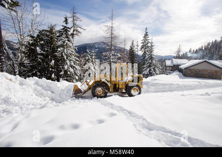 02/19/2018 Snow event. Ein Caterpillar 950 mit Gummibereifung artikuliert Lader Schneeräumen auf einem Berg Straße nördlich des Noxon, in Sanders County Montana. Stockfoto