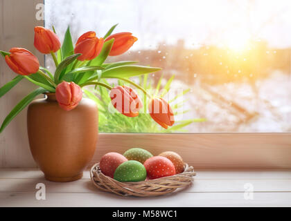 Frühling Hintergrund mit grünem Gras, Ostereier und Bündel von orange Tulpen im Fenster Board auf einen Sonnenuntergang nach Regen. Platz für Ihren Text. Stockfoto