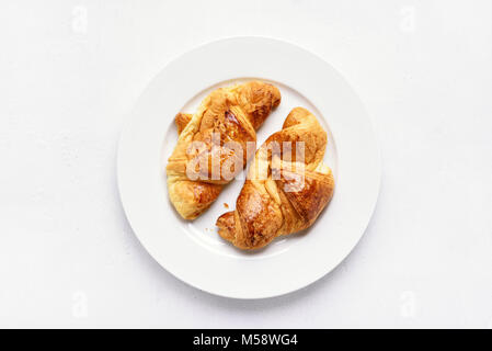 Croissants auf die Platte über der weißen Stein Hintergrund. Ansicht von oben, flach Stockfoto