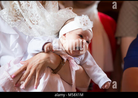 Belarus, die Stadt Gomel. Juni 10, 2017. Kirche am regionalen Krankenhaus. Die Taufe eines Kindes. ein Baby Kind gähnt in seine Arme an den Ritus der bapti Stockfoto