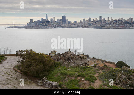 Die San Francisco Skyline gesehen von Alcatraz, der Exerzierplatz und die Ruinen von abgerissenen Gebäuden im Vordergrund. Stockfoto