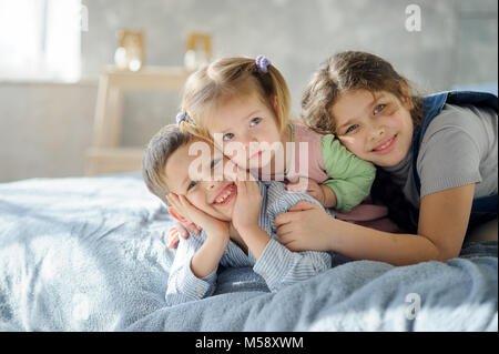 Zwei Schwestern und einen Bruder. Drei Kinder aus der gleichen Familie liegen auf dem Bett. Stockfoto