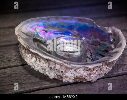 Seashell mit Kerze. Dekorative irisierende Abalone Muschel. Close-up. Stockfoto