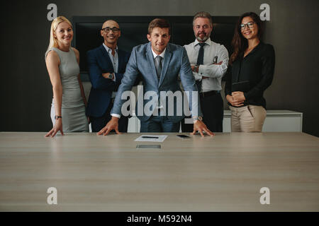 Portrait von glücklichen Gruppe von Geschäftsleuten stehen zusammen am Tisch und Kamera. Corporate Business Group im Amt. Stockfoto