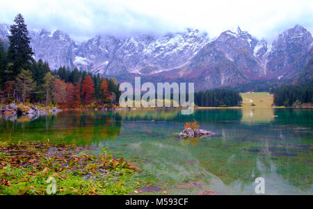 Wunderschönen Lago di Fusine Bergsee im Herbst und Mangart Berg im Hintergrund bei Sonnenuntergang in Nord Italien Alpen, Europa Stockfoto