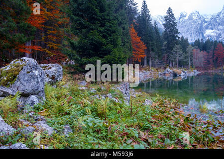 Wunderschönen Lago di Fusine Bergsee im Herbst und Mangart Berg im Hintergrund bei Sonnenuntergang in Nord Italien Alpen, Europa Stockfoto