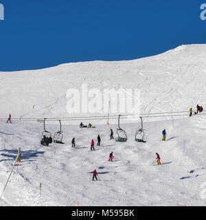 La Thuile, Italien - 18.Februar 2018: die Sesselbahn am italienischen Skigebiet auf schneebedeckten Alpen und Skifahrer und Snowboarder auf der Piste - Wintersport Konzept Stockfoto