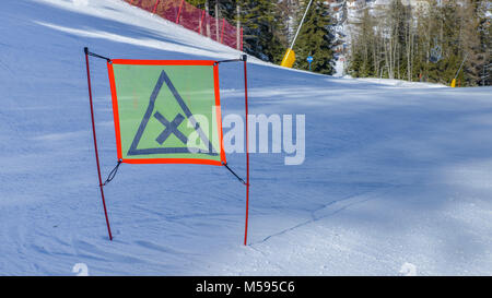 Schild mit Warnung auf der Piste, in den italienischen Alpen erfasst Stockfoto