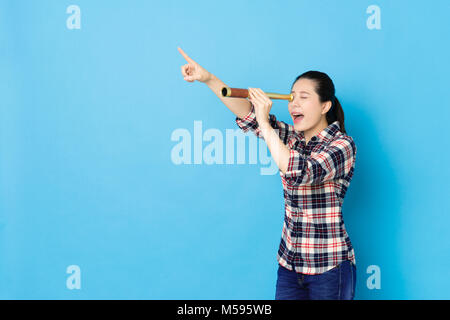 Gerne schöne Frau zeigt ferner, als Sie mit Stretch Teleskop Diagnosegerät Ziel auf der blauen Wand Hintergrund isoliert. Stockfoto