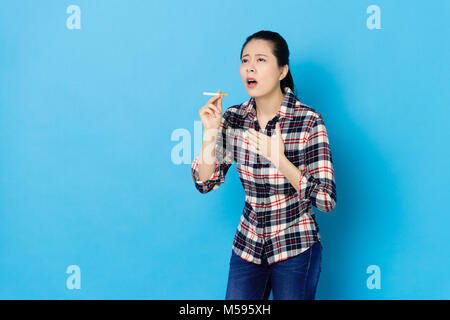 Attraktive junge Mädchen rauchen lange Zeit Gefühl schmerzlich und Husten, wenn Sie die Zigarette, die in blauen Hintergrund. Stockfoto