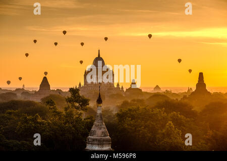 Heißluftballons über den Thatbyinnyu Tempel und Pagoden von Bagan und den nebligen Ebenen der archäologischen Stätte in der Sunrise fliegen Stockfoto