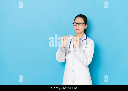 Professionelle junge Arzt Frau Zigarette rauchen concepte präsentieren auf der blauen Wand Hintergrund isoliert Beenden biegen. Stockfoto
