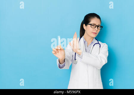 Schöne junge Frau Krankenhaus Arzt verweigerte Zigarette und zeigen Sie das Rauchen Konzept auf der blauen Wand Hintergrund isoliert. Stockfoto