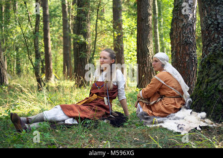 Gnezdovo, Russland - August 09, 2014, zwei Mädchen in der alten russischen Kleidung sitzen auf dem Gras während des Festivals der historischen Rekonstruktion Stockfoto