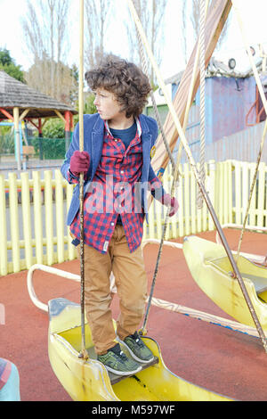 Porträt einer lockigen Haaren kleinen Jungen mit Sommersprossen spielen im Freien an einem Park Stockfoto