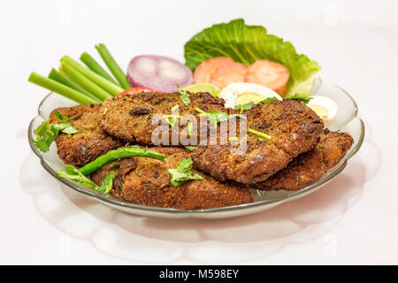 Leckere indische Bengali starter Gericht knusprige bhetki Fisch braten, garniert mit Bohnen mit Scheiben von Ei, Tomate, Karotte und Zwiebel. Stockfoto