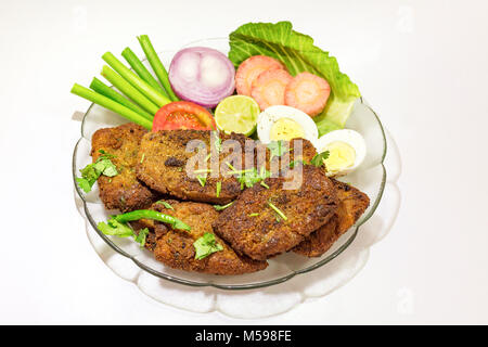 Leckere indische Bengali starter Gericht knusprige bhetki Fisch braten, garniert mit Bohnen mit Scheiben von Ei, Tomate, Karotte und Zwiebel. Stockfoto