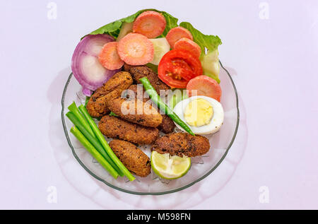 Knusprig frittierte Fisch finger Indischen starter Teller garniert mit Bohnen mit Scheiben von Ei, Tomate, Karotte und Zwiebel Stockfoto