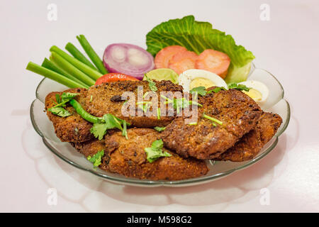 Leckere indische Bengali starter Gericht knusprige bhetki Fisch braten, garniert mit Bohnen mit Scheiben von Ei, Tomate, Karotte und Zwiebel. Stockfoto