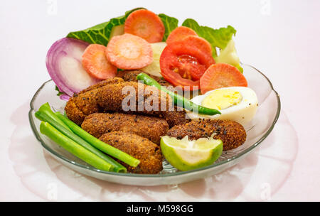 Knusprig frittierte Fisch finger Indischen starter Teller garniert mit Bohnen mit Scheiben von Ei, Tomate, Karotte und Zwiebel Stockfoto