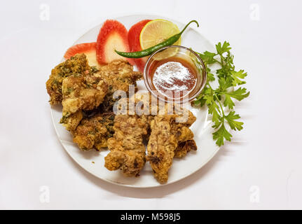 Frittierte spicy Chicken pakora serviert mit Tomatensauce und geschnittene Karotte Zitrone mit korianderblatt mit grünem Chili. Eine beliebte indische starter Gericht. Stockfoto