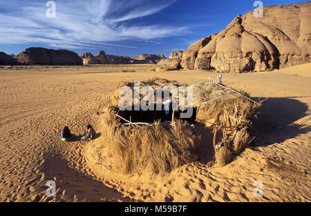 Libyen. In der Nähe von Ghat. Sahara. Akakus (acacus) National Park. Mann der Tuareg Stamm vor seinem Haus aus Stroh (zeriba). Stockfoto