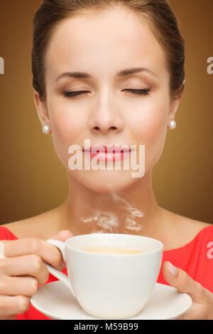 Schöne Frau im roten Kleid mit Tasse Kaffee Stockfoto