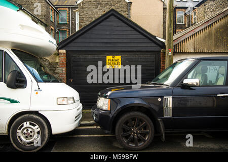 Rücksichtslose Autofahrer UK: Zwei geparkte Fahrzeuge blockieren den Eintritt in eine private Garage trotz dass das Parken, behinderte Fahrer" zu unterzeichnen. Großbritannien Stockfoto