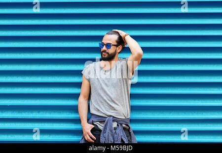 Mann in der Sonnenbrille über Gerippte blaue Wand posieren Stockfoto