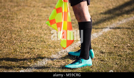 Fußball Fußball Schiedsrichter assistent steht an der Seitenlinie beobachten das Spiel mit Fahne in der Hand. Verschwommen grünen Hintergrund, aus der Nähe. Stockfoto