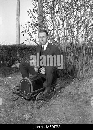 Ein reifer Mann genießt eine Fahrt auf einem Spielzeug Traktor, Ca. 1920. Stockfoto