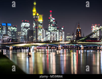 Die beleuchtete Skyline von Hochhaus Büro Gebäude stehen hoch über dem Floesserbruecke (C), der sich über den Main, Frankfurt, Deutschland, 20. Februar 2018. (Hinweis: Bild mit einem Tilt-shift Objektiv) Foto: Frank Rumpenhorst/dpa genommen Stockfoto