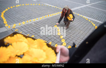 Stuttgart, Deutschland. 21 Feb, 2018. Anne-Mareyke Boettcher zur Festlegung der Gerbera Blumen in der Form eines Friedenszeichen während eines künstlerischen Kampagne auf der 60. Jahrestag der 'Frieden' Zeichen in Stuttgart, Deutschland, 21. Februar 2018. Der baden-wuerttembergische Verband der Deutschen Friedensgesellschaft - Vereinigte Gegner der Wehrpflicht legte um 200 Blumen in der Form eines Frieden unterschreiben und dann verteilt, um die Blumen zu den Passanten. Credit: Sebastian Gollnow/dpa/Alamy leben Nachrichten Stockfoto